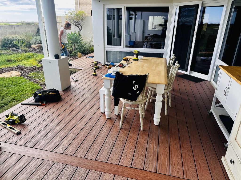 Red-brown composite alfresco deck with a picture frame border during install